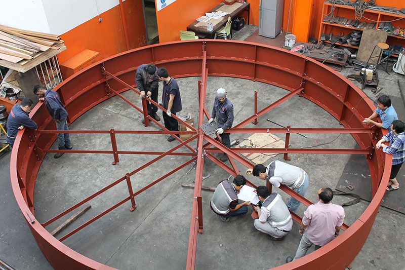 A team assembling a large circular steel frame