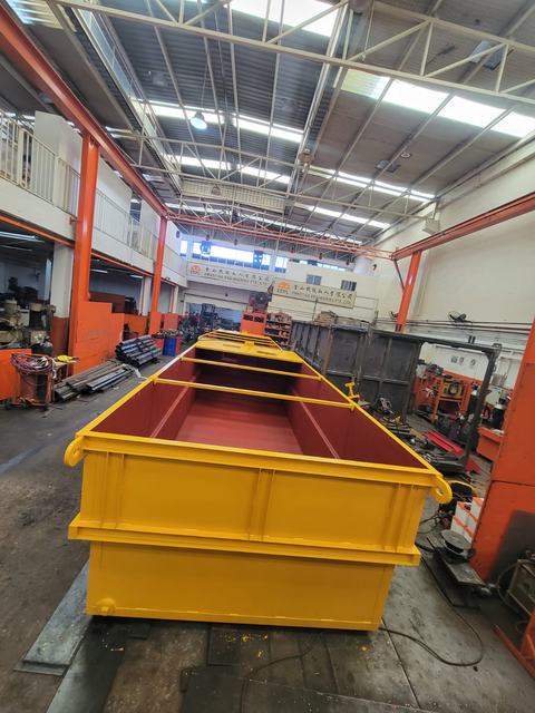 Yellow steel skip with lifting lugs and a red-painted interior