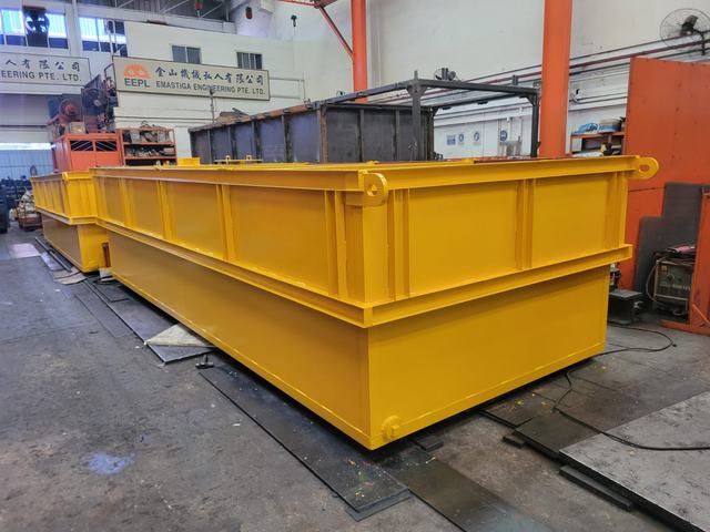 Two large yellow steel skips with lifting lugs in the workshop