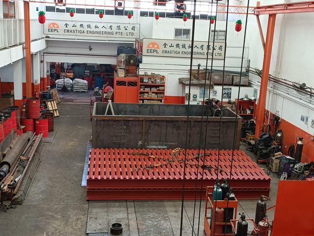 Overview of the Emastiga workshop with red-painted steel grating frames