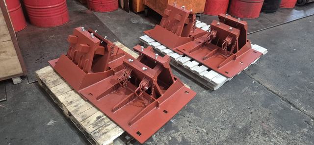 Red-painted steel fixtures with chains, on pallets