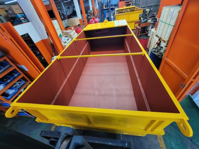 Inside a yellow steel skip with a red-painted interior