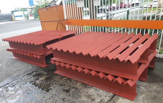 Red-painted steel grating frames stacked outdoors